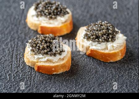 Baguette-Scheiben mit Frischkäse und schwarzem Kaviar Stockfoto