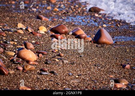 Felsen am Ufer des Strandes, unfokussierter Hintergrund, niemand, Nahaufnahme, sonnig, große und kleine Steine Stockfoto