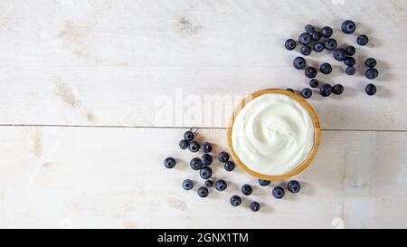 Draufsicht auf weißen Joghurt mit reifen blauen Früchten auf einem Tisch mit Kopierfläche. Schüssel mit gesunden Lebensmitteln und Heidelbeeren reich an Vitaminen zum Frühstück serviert Stockfoto