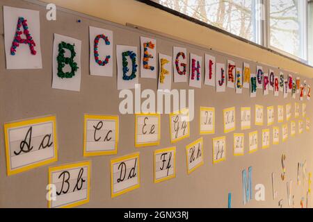 Farbige Buchstaben, Alphabet in Block und kursiv an der Wand einer Grundschule Stockfoto