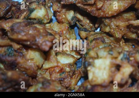 Nahaufnahme mit selektivem Fokus auf knuspriges Becken Pakora/Pakoda oder Patties sind beliebte indische oder pakistanische Street Food Snack, serviert mit grünem Salat Stockfoto