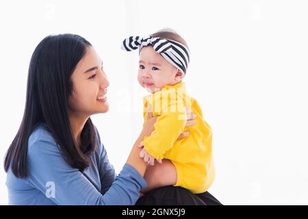 Portrait von schönen jungen asiatischen Mutter spielen und lächeln zusammen mit seinem neugeborenen kleinen Baby zu Hause, Eltern Mutter und kleines Kind entspannen in der Stockfoto