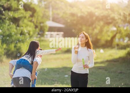 Happy Asian Lifestyle Familie Mutter, Vater und kleine niedliche Mädchen Kind Spaß zusammen und genießen im Freien spielen Seifenblasen in der Garde Stockfoto