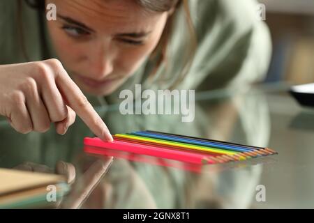 Zwanghafte Frau, die Bleistifte genau auf einem Glas ausrichtet Tabelle Stockfoto