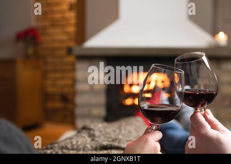Verliebte Paare sitzen in einem gemütlichen Zimmer mit Kamin auf einem Sofa mit einem Glas Wein. Familie und Liebe Konzept. Stockfoto