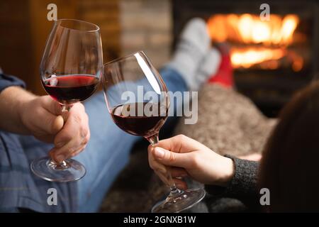 Verliebte Paare sitzen in einem gemütlichen Zimmer mit Kamin auf einem Sofa mit einem Glas Wein. Familie und Liebe Konzept. Stockfoto