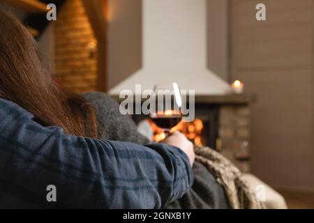 Verliebte Paare sitzen in einem gemütlichen Zimmer mit Kamin auf einem Sofa mit einem Glas Wein. Familie und Liebe Konzept. Stockfoto