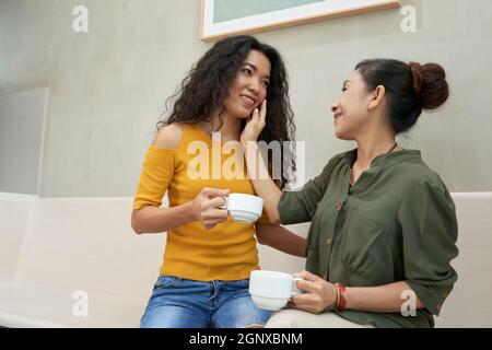 Positive attraktive junge asiatische Frau, die eine warme Beziehung zur älteren Mutter hat: Sie trinken Kaffee im Café Stockfoto