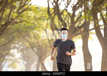 Junger Mann in Gesichtsmaske und läuft im Park Stockfoto