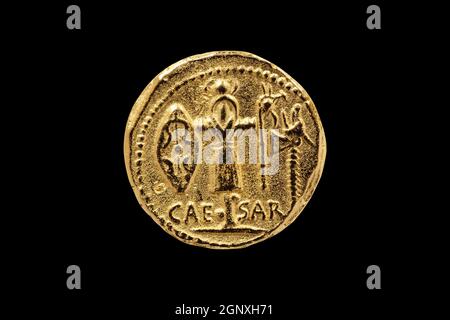 Rückseite einer Replik der römischen Aureus Goldmünze Julius Caesar mit einer Trophäe der gallischen Waffen zwischen geschlagen 48-47 v. Chr. Ausschneiden und auf einem Blac isoliert Stockfoto