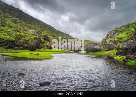 Kleine Stein Wishing Brücke über See im grünen Tal, Gap of Dunloe in Black Valley, Ring of Kerry, County Kerry, Irland Stockfoto