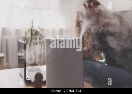 Freiberuflerin verwendet einen Hausbefeuchter am Arbeitsplatz, um relative Luftfeuchtigkeit und Mikroklima am Arbeitsplatz des Heimbüros mit zu erhalten Stockfoto