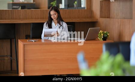 Ärztin, Apothekerin oder Therapeutin, die an ihrem Schreibtisch im Krankenhaus arbeitet und Medikamente verordnet Stockfoto
