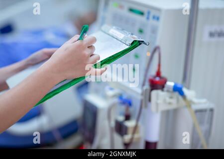 Die Dialysekrankenschwester überprüft das Dialysegerät vor dem Ersatz einer Nierenfunktionsstörung oder Nierenversagen auf der Intensivstation. Stockfoto