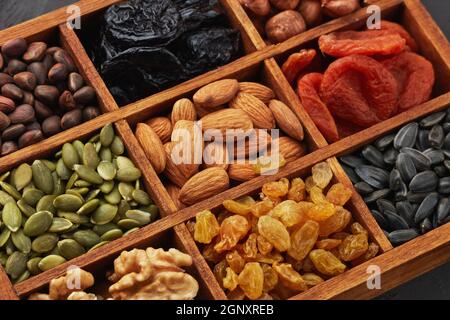 Verschiedene Sorten von Nüssen, Samen und getrockneten Früchten liegen in Holzkiste. Draufsicht. Gesunde Ernährung. Vegetarische Ernährung Stockfoto