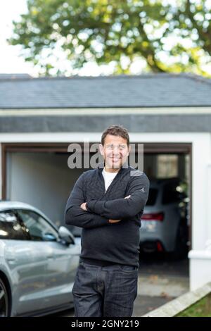 Männlich mit seinen Elektroautos vor seiner Hausgarage Stockfoto