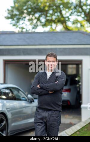 Männlich mit seinen Elektroautos vor seiner Hausgarage Stockfoto