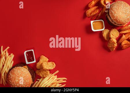 Zwei Hamburger und pommes Frites, Saucen auf rotem Hintergrund. Fast Food. Draufsicht. Stockfoto