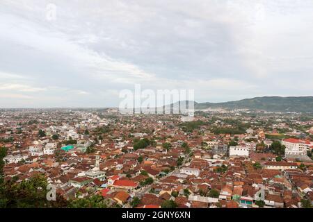 Luftaufnahme der dichten Stadt und Bevölkerung von Bandar Lampung Stadtbild mit Horizont und Küstenhintergrund. Seltsame Wolkenbildung. Wolkiger blauer Himmel. Stockfoto