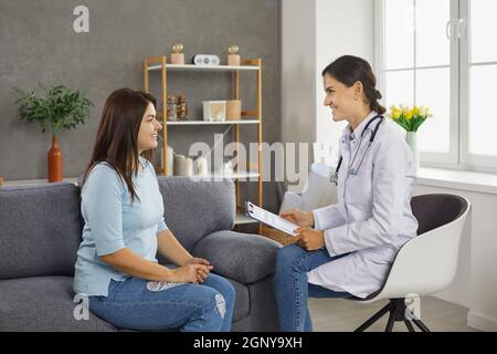 Eine freundliche Ärztin oder Krankenschwester kommuniziert mit einer Patientin, während sie ihr Zuhause besucht. Stockfoto