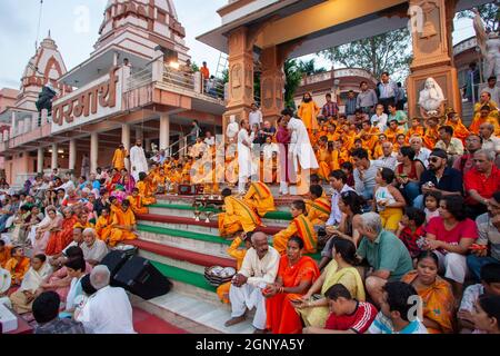 Zuschauer, Gläubige, Anhänger und Priester in orangefarbenen Gewändern in der heiligen Stadt Rishikesh in Uttarakhand, Indien während der abendlichen Lichtzeremonie cal Stockfoto