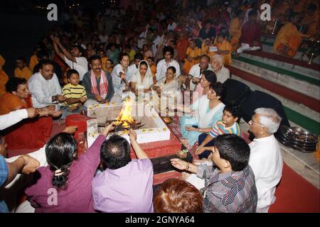 Zuschauer, Gläubige, Anhänger und Priester in orangefarbenen Gewändern in der heiligen Stadt Rishikesh in Uttarakhand, Indien während der abendlichen Lichtzeremonie cal Stockfoto