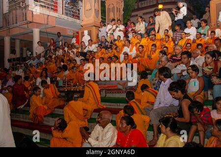 Zuschauer, Gläubige, Anhänger und Priester in orangefarbenen Gewändern in der heiligen Stadt Rishikesh in Uttarakhand, Indien während der abendlichen Lichtzeremonie cal Stockfoto