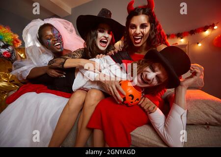 Junge Männer und Frauen, die in Kostümen verkleidet sind, haben Spaß auf einer verrückten Halloween-Party Stockfoto