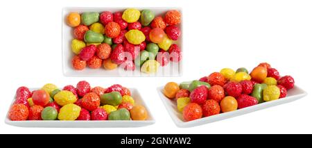 Kauen von buntem Kaugummi in Form von Früchten auf einem Teller, der auf weißem Hintergrund isoliert ist. Unterschiedliche Betrachtungswinkel. Stockfoto