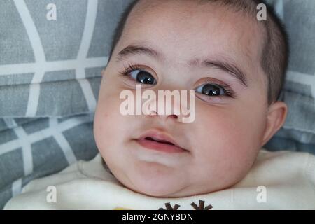 Baby-Mädchen mit schönen Gesicht, große Augen und niedliche Gesichtsgeste. Baby Mädchen mit schwarzen Augen starrte auf die Kamera. Stockfoto