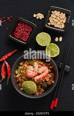 Pad Thai. Gebratene Reisnudeln mit Hühnerfleisch, Garnelen, Rührei, Erdnüssen, Gemüse und Sauce in einer Schüssel auf schwarzem Hintergrund. Draufsicht. Tha Stockfoto