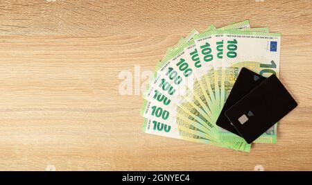 Bargeld im Vergleich zu Kreditkarten. Euro-Währung auf Holzhintergrund. Stockfoto