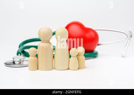 Familie von Holzfiguren von Männern auf Hintergrund von rotem Herz und Stethoskop, Krankenversicherungskonzept, Nahaufnahme Stockfoto