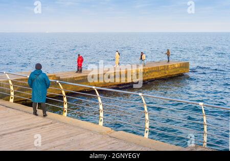 ODESSA, UKRAINE - 26. NOVEMBER 2020: Menschen an einem Pier vor dem Balckmeer in Odessa an einem sonnigen Herbsttag Stockfoto