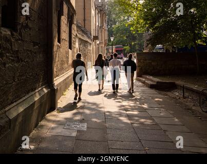 Menschen, die sich von der Kamera durch die Schatten in St. Giles, Oxford, entfernen, eine Straße, die durch das Zentrum von Oxford führt Stockfoto