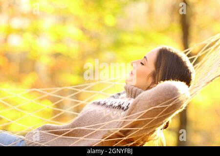 Seitenansicht Porträt der Frau, die auf Hängematte in liegend ruht Herbstlicher Wald Stockfoto