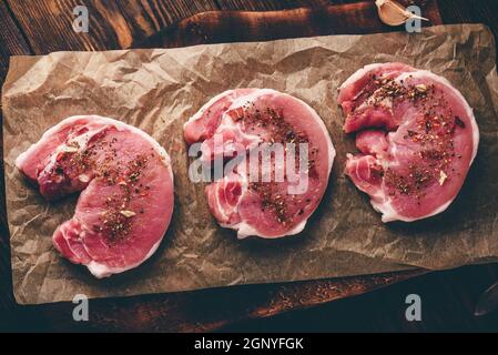 Raw Schweinelende Steaks mit verschiedenen Gewürzen, auf Backpapier Stockfoto