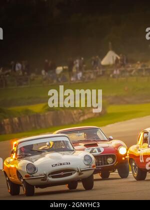 E Type Jaguar und Ferrari 250 bei Sonnenuntergang beim Goodwood Revival 2021, West Sussex, großbritannien Stockfoto