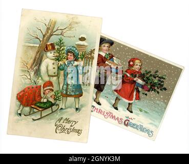 Original geprägte, edwardianische Weihnachtsgrüße Postkarten, gedruckt in Deutschland, von niedlichen kleinen Kindern, die zu dieser Zeit modische Winterkleidung tragen, einen Schneemann bauen und Geschenke tragen, um 1910, Großbritannien Stockfoto