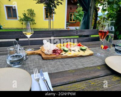 Ein traditioneller kalter Snack mit Wurst, Schinken, Speck, Käse und Aufstrichen, der oft in Tavernen angeboten wird, so genannte Buschenschank, mit einem Glas des Stockfoto