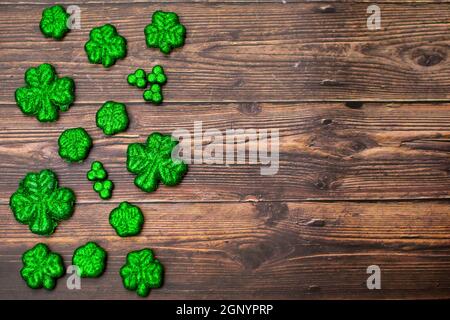 Glitter bedeckt vier Blatt Clovers für Saint Pattys Day Füllung Die Hälfte des Rahmens auf einem Holzhintergrund Stockfoto