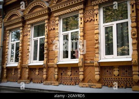 Altes historisches Holzhaus im russischen Stil mit geschnitzten Verkleidungsbrettern und einer Figur eines Schweins, die aus dem Fenster schaut Stockfoto