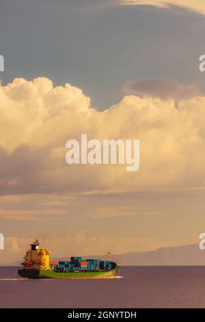 Frachtschiff in der Nähe Capo Peloro Leuchtturm in Punta del Faro an der Straße von Messina, nordöstlichste Landzunge von Sizilien, Italien Stockfoto