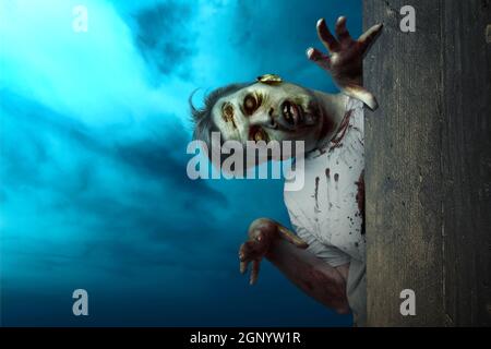 Furchteinflößende Zombies, die hinter der Holzwand mit dem Hintergrund der Nachtszene stehen Stockfoto