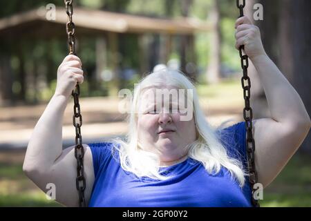 Erwachsene Albino Frau genießen spielen auf einem Park Schaukel Stockfoto