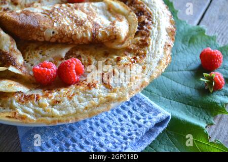 Fasching-Maslenitsa-Festessen. Russische oder weißrussische Pfannkuchen Blini mit Himbeermarmelade, Honig, frischer Creme und rotem Kaviar Stockfoto