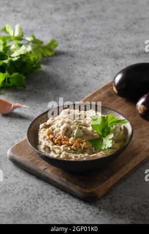 Baba ganoush aus gebackener Aubergine mit Petersilie, Knoblauch und Olivenöl. Vertikales Format. Nahaufnahme. Nahöstliche Küche, veganer Hummus. Stockfoto