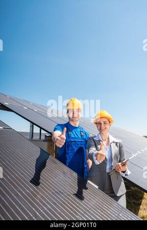 Arbeiter und Investor in Solarkraftwerk zeigt auf die Sonne Stockfoto