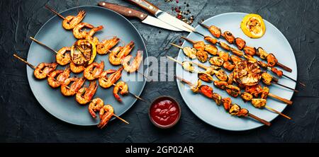 Köstliche geröstete Garnelen und Muscheln auf Holzspießen Stockfoto