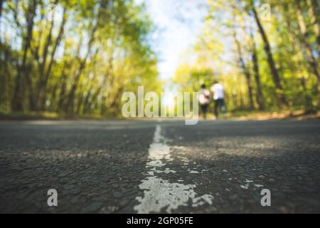 Die asphaltierte Straße in den Wald: Nahaufnahme, Perspektive, verschwommenen Hintergrund Stockfoto